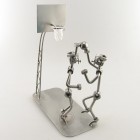 Steelman stepping on a soccer ball and holding up a trophy metal art figurine