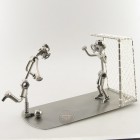 Steelman stepping on a soccer ball and holding up a trophy metal art figurine